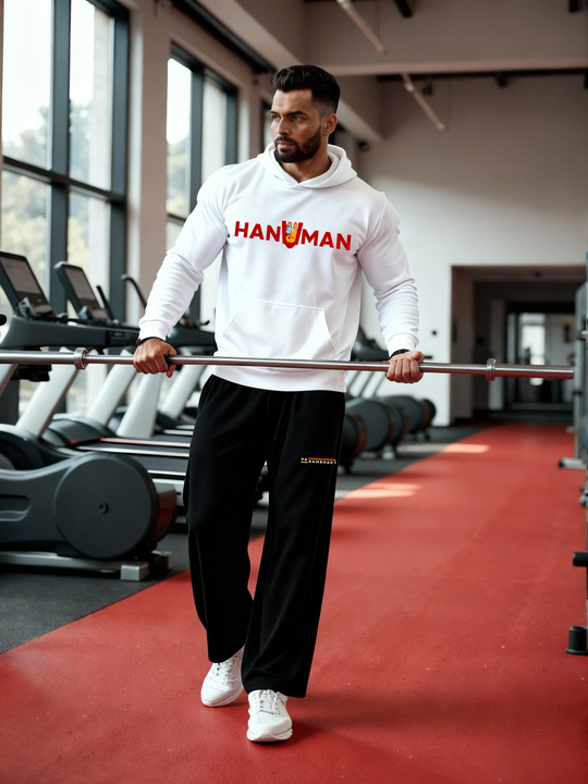 Man wearing a white Parambhakt ‘Hanuman in U’ Training Hoodie holding a barbell while walking inside a gym.