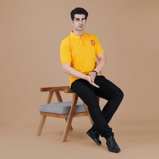 Man wearing the yellow Parambhakt Ganeshji Polo while seated in a modern chair, showcasing the subtle Ganesh ji artwork on the chest.