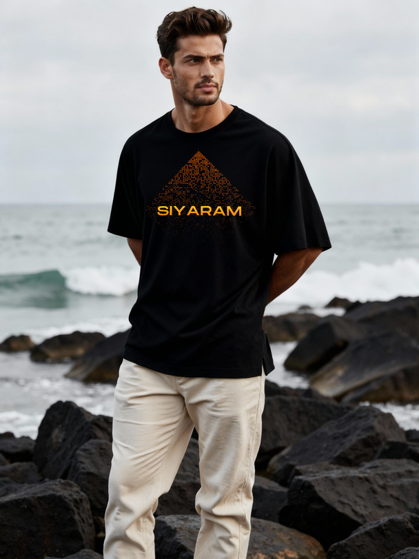Man standing by the sea wearing Parambhakt Siyaram oversized T-shirt.