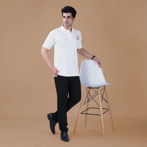 Man wearing the white Parambhakt Veer Hanumanji Polo T-shirt standing beside a chair, showcasing a modern spiritual lifestyle look.
